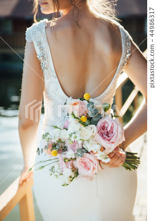 View of unrecognazible young woman in wedding dress standing by back and looking away. 44986317