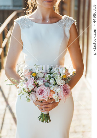 View of unrecognazible young woman in wedding dress standing by back and looking away. View of unrecognazible young woman in wedding dress standing by back and looking away. 44986319