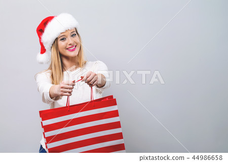 Young woman with santa hat holding a shopping bag Young woman with santa hat holding a shopping bag 44986658