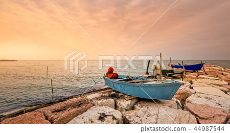 Fishing boat moored on cliff at sunset. 44987544