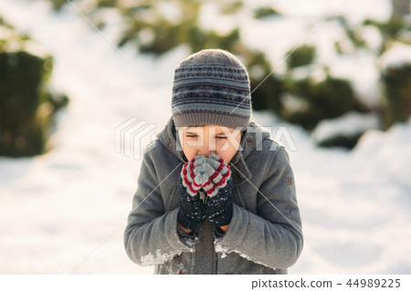 A boy warms his hands from the cold in winter 44989225