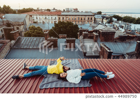 A handsome guy and a young girl lie on the roof and hold the smarfons. A handsome guy and a young girl lie on the roof and hold the smarfons. 44989750