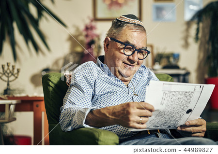 Jewish senior with glasses in the armchair reading a torah book Jewish senior with glasses in the armchair reading a torah book 44989827