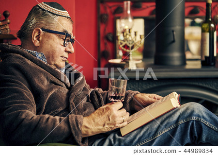 Jewish senior reading a torah book and drinking kosher wine Jewish senior reading a torah book and drinking kosher wine 44989834
