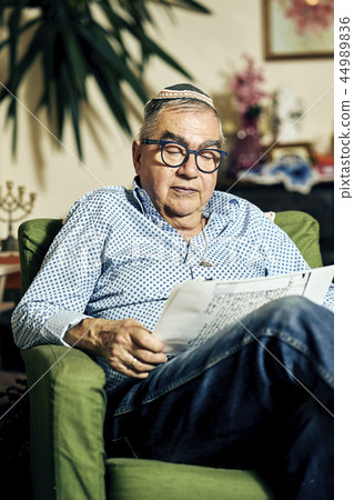 Jewish senior with glasses in the armchair reading a torah book Jewish senior with glasses in the armchair reading a torah book 44989836