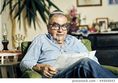 Jewish senior with glasses in the armchair reading a torah book Jewish senior with glasses in the armchair reading a torah book 44989843