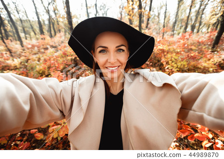 happy woman making selfie in the autumn park full of yellow leaves happy woman making selfie in the autumn park full of yellow leaves 44989870