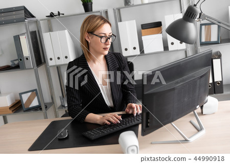 A young girl working at a computer in the office. 44990918