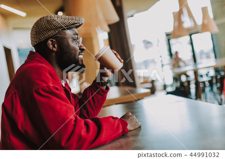 Young man looking glad while sitting alone and drinking coffee 44991032