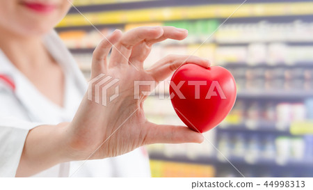 Doctor holding a red heart at hospital office. Doctor holding a red heart at hospital office. 44998313