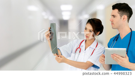 Doctors discussing and looking at x ray film. Doctors discussing and looking at x ray film. 44998323