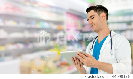 Pharmacist using tablet computer at pharmacy. 44998356