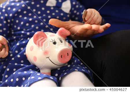 Child little girl arm putting coins into piggybank Child little girl arm putting coins into piggybank 45004627