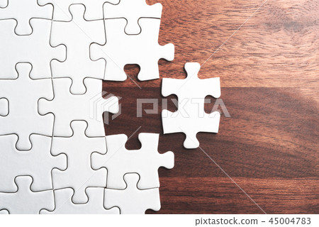 Assemble a plain jigsaw puzzle on a wooden table. Assemble a plain jigsaw puzzle on a wooden table. 45004783