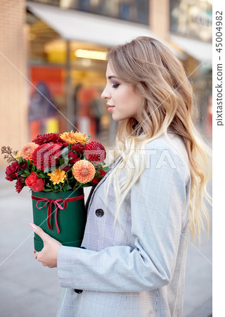 Caucasian fashion woman standing on the street near storefront shop windows holding flower-box with Caucasian fashion woman standing on the street near storefront shop windows holding flower-box with 45004982