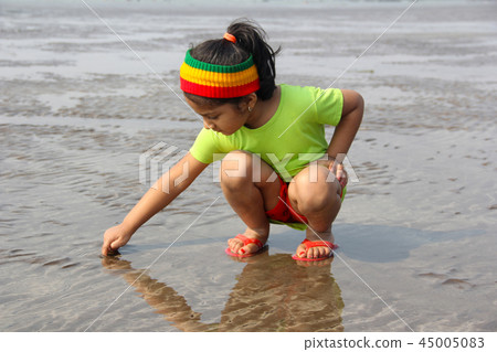 Little girl writing on wet sand Alibag beach India Little girl writing on wet sand Alibag beach India 45005083