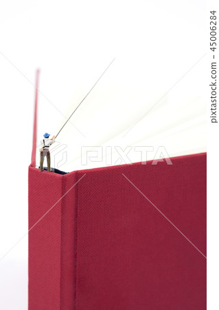 Miniature man fishing from above with red book 45006284