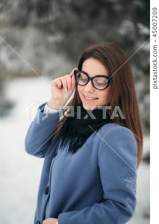Portrait of happy young woman wearing winter hat and scarf stands next to the Christmas tree. black Portrait of happy young woman wearing winter hat and scarf stands next to the Christmas tree. black 45007209