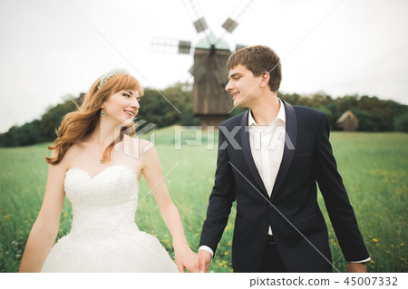 Emotional beautiful bride hugging newlywed groom at a field closeup 45007332