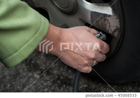 woman putting air into the tire from tire valve woman putting air into the tire from tire valve 45008533
