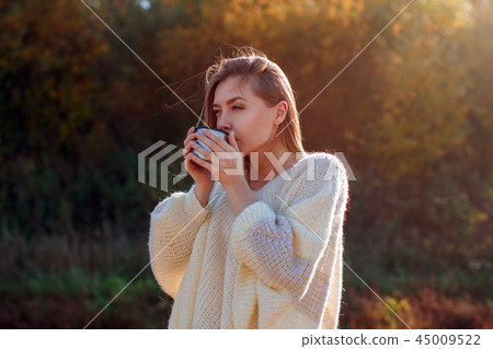 Beautiful admiring woman drinking hot tea from thermos cup 45009522