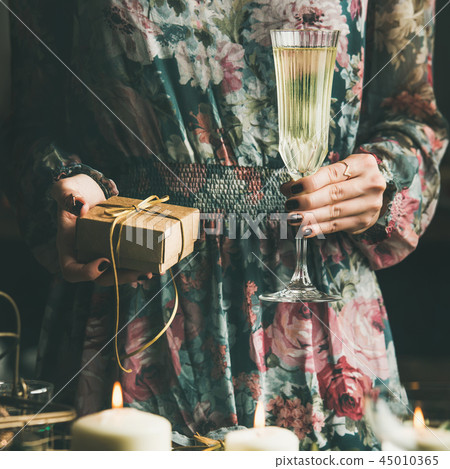 Woman holding glass of champaigne and gift box during Christmas 45010365