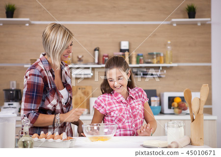Cute little girl and her mother cooking something delicious Cute little girl and her mother cooking something delicious 45010671