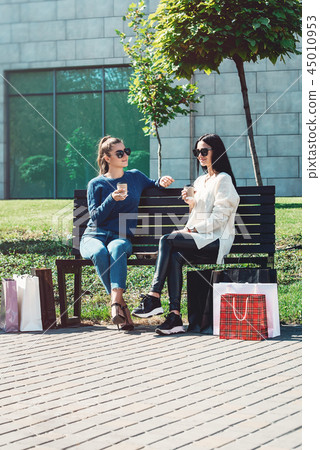 Beautiful girls with paper bags outside shopping mall Beautiful girls with paper bags outside shopping mall 45010953