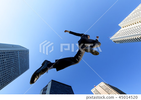 One businessman in a suit who jumps against the blue sky back on the building street. Challenge, Effort, Success, Cheerful Image 45014520