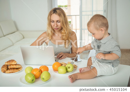 Mom chooses a cartoon for a child during breakfast Mom chooses a cartoon for a child during breakfast 45015104