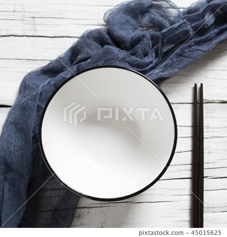 empty bowl and pair of chopsticks on a white table 45015625
