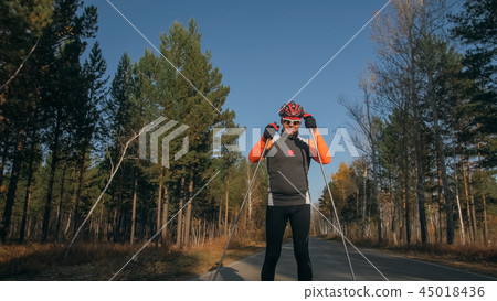 Training an athlete on the roller skaters. Biathlon ride on the roller skis with ski poles, in the Training an athlete on the roller skaters. Biathlon ride on the roller skis with ski poles, in the 45018436