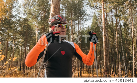 Training an athlete on the roller skaters. Biathlon ride on the roller skis with ski poles, in the 45018441