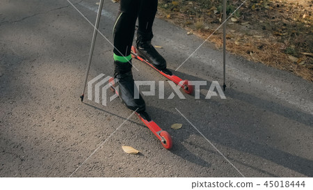 Training an athlete on the roller skaters. Biathlon ride on the roller skis with ski poles, in the Training an athlete on the roller skaters. Biathlon ride on the roller skis with ski poles, in the 45018444