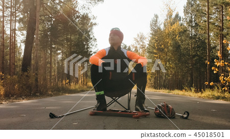 Training an athlete on the roller skaters. Biathlon ride on the roller skis with ski poles, in the 45018501