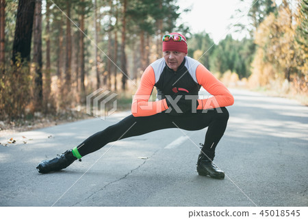 Training an athlete on the roller skaters. Biathlon ride on the roller skis with ski poles, in the 45018545
