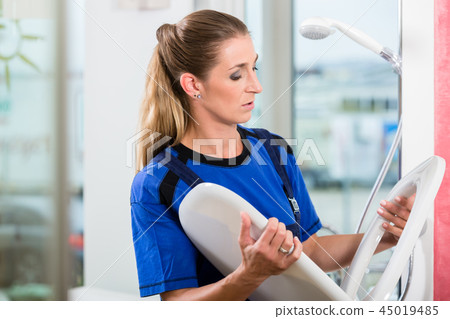 Female maintenance worker checking the quality of a toilet seat Female maintenance worker checking the quality of a toilet seat 45019485