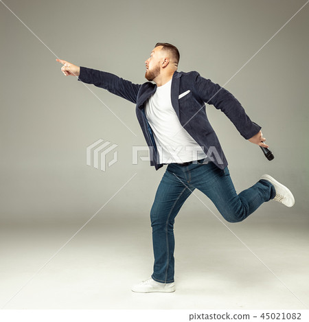 Young man with microphone on gray background, leading with microphone 45021082