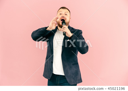 Young man with microphone on pink background, leading with microphone 45021196