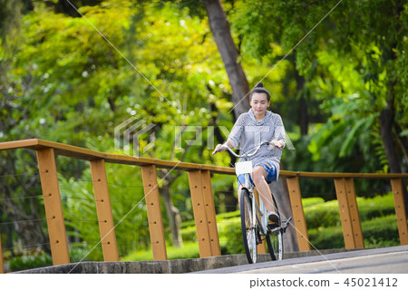 Young beautiful woman riding a bicycle in a park 45021412