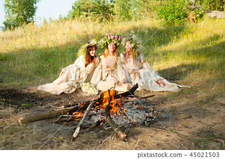 Beautiful women with flower wreath near bonfire Beautiful women with flower wreath near bonfire 45021503