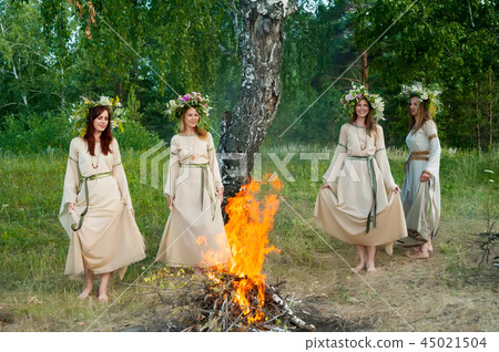 Beautiful women with flower wreath near bonfire 45021504