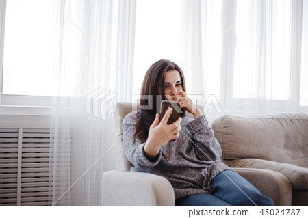Cheerful woman typing on mobile phone at home 45024787