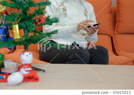 woman using smart phone at home during xmas. christmas holiday new year celebration season greetings woman using smart phone at home during xmas. christmas holiday new year celebration season greetings 45025813