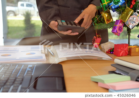 financial adviser use calculator to calculate revenue & budget. accountant doing accounting during christmas holiday financial adviser use calculator to calculate revenue & budget. accountant doing accounting during christmas holiday 45026046