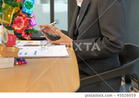 financial adviser use calculator to calculate revenue & budget. accountant doing accounting during christmas holiday financial adviser use calculator to calculate revenue & budget. accountant doing accounting during christmas holiday 45026059
