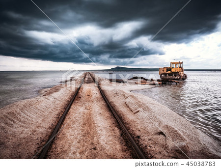 Old rusty tractor thrown in salt water razy rails 45038783