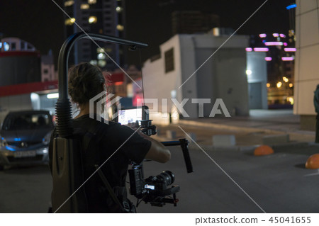 Professional videographer holding camera on 3-axis gimbal which mounted on easy rig. Videographer Professional videographer holding camera on 3-axis gimbal which mounted on easy rig. Videographer 45041655