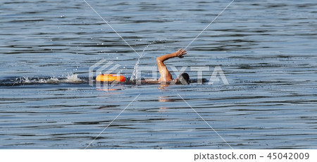 Swimming in water with orange flotation device Swimming in water with orange flotation device 45042009
