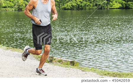 runner with phone passing a lake in the woods runner with phone passing a lake in the woods 45042059